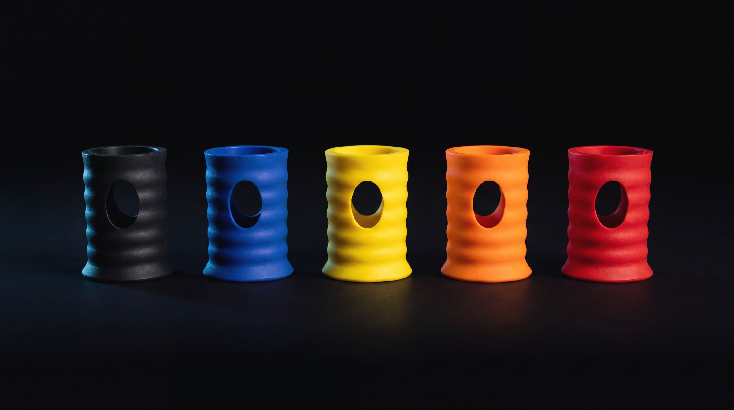 KRVE REACT dampeners in black, blue, yellow, orange and red lined up on a dark surface